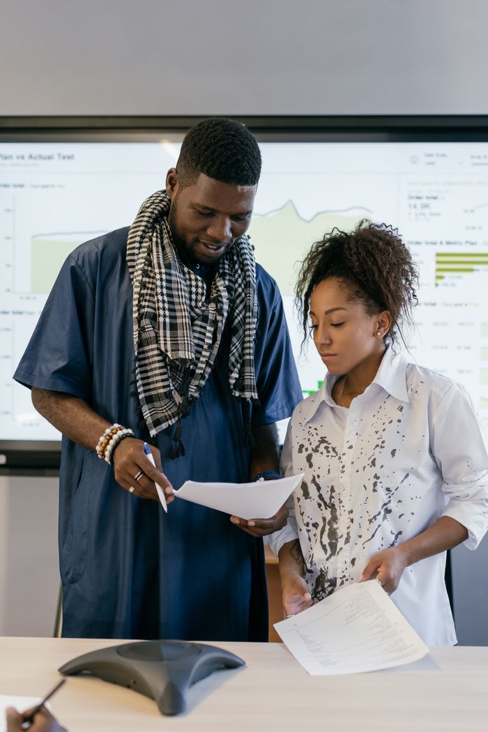 Two colleagues reviewing documents in a business meeting setting.